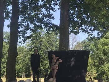 People standing by tree trunk in forest