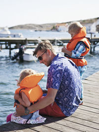 Father with two children sitting on pier