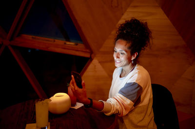 Woman using a mobile phone while relaxing in a dome tent.
