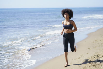 Young woman running at beach on sunny day