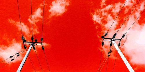 Low angle view of telephone pole against orange wall