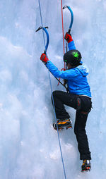 Rear view full length of woman ice climbing