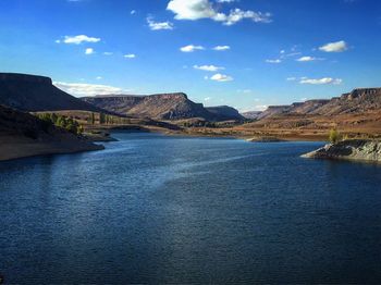 Scenic view of river by mountains against sky