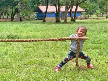 Full length portrait of smiling boy on grassy field
