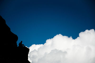 Low angle view of silhouette man against blue sky