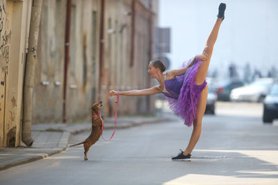 Full length of young woman jumping in city