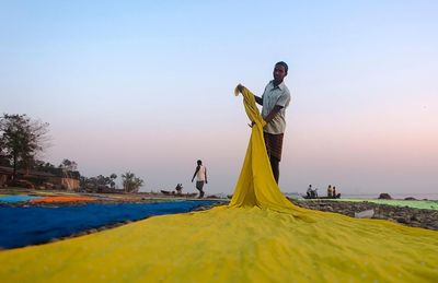 People standing on yellow water against clear sky