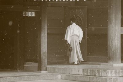 Rear view of woman standing against wall