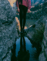 Low section of man standing on rock by lake