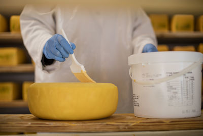 Cheese factory worker applying wax on cheese