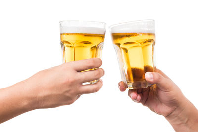 Cropped image of hand holding beer glass against white background