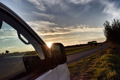 Car on landscape against sky during sunset