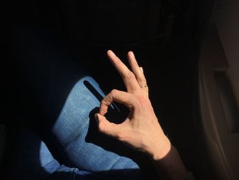 Cropped image of hand showing ok sign in airplane