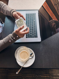 Woman working remotely on her laptop computer managing her work sitting in a cafe