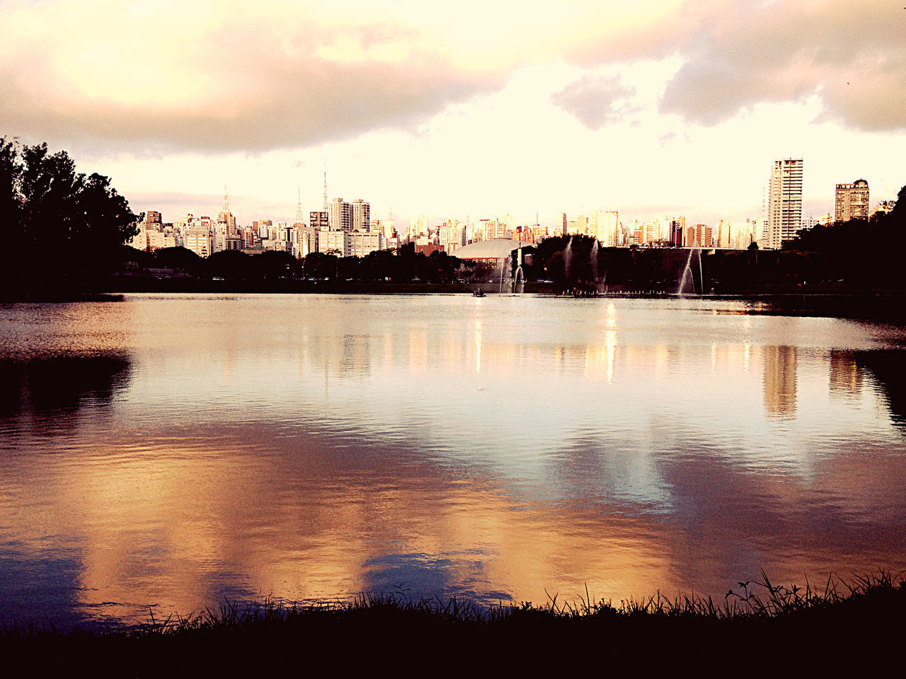 SILHOUETTE BUILDINGS BY RIVER AGAINST SKY