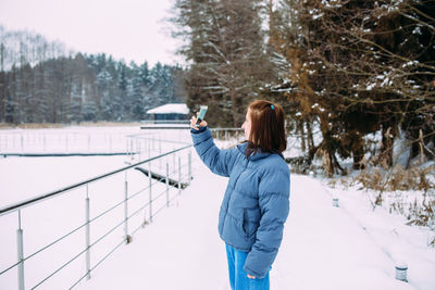 Rear view of woman walking on snow covered field