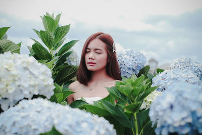 Young woman with eyes closed amidst flowering plants