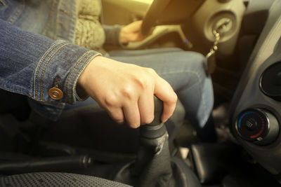 Close up of the hand of a woman on the gear lever while driving inside her vehicle with yellow light