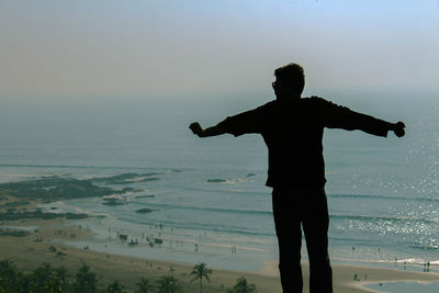 Rear view of man standing on beach against sky