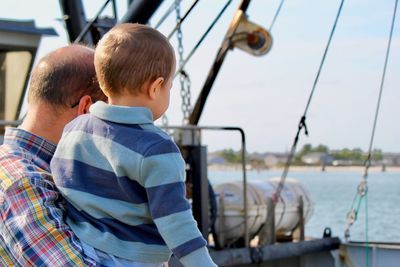 Rear view of father and son on boat