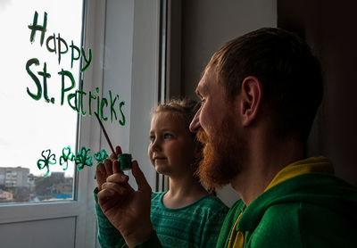 Drawing st. patrick's day father daughter painting green three-leaved shamrocks.stay home new normal