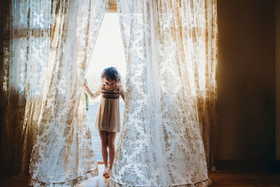 Rear view of woman standing against window