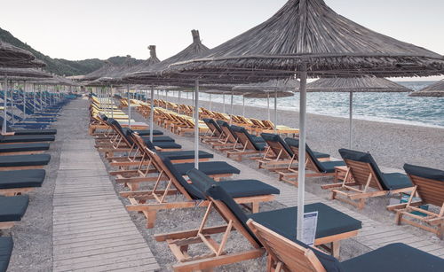 Row of chairs on beach against clear sky