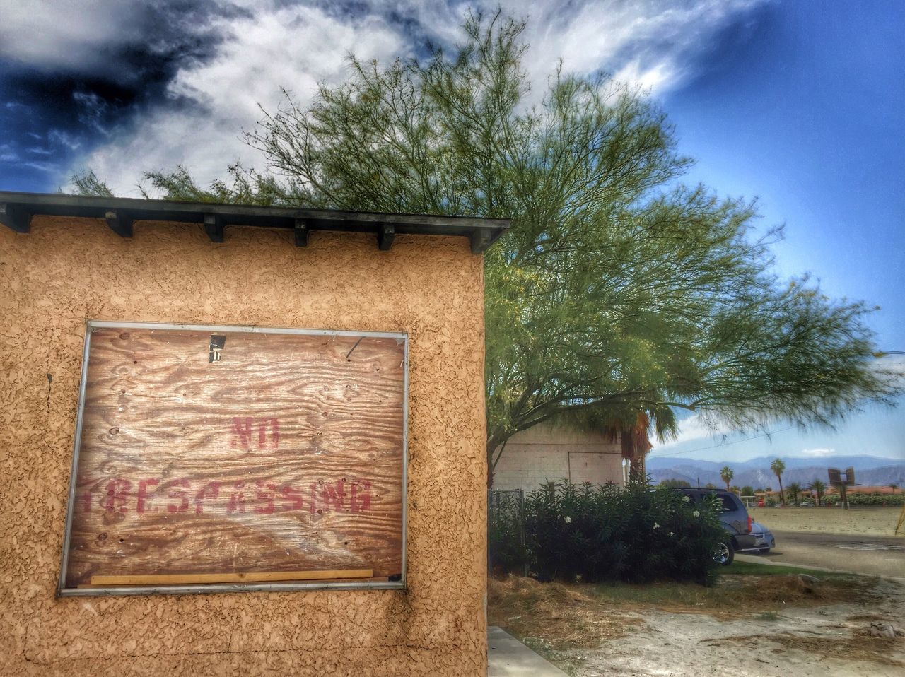 building exterior, architecture, built structure, sky, tree, cloud - sky, house, cloud, cloudy, day, outdoors, residential structure, old, wall - building feature, text, no people, residential building, low angle view, graffiti, abandoned