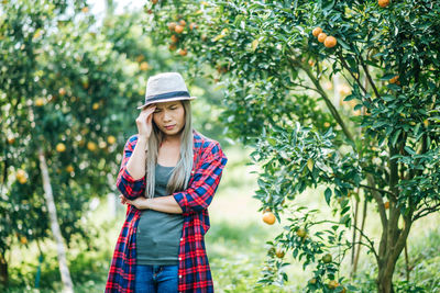 Portrait of smiling young woman standing against tree