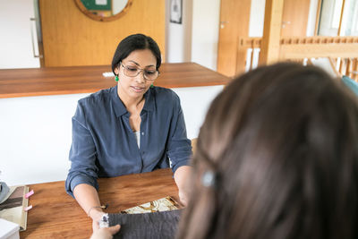 High angle view of female design professionals discussing while sitting at table in home office