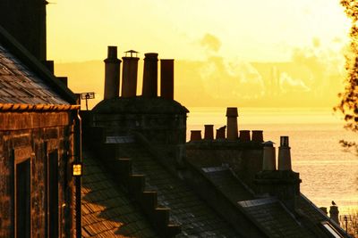 Rear view of woman standing on bridge against sky during sunset