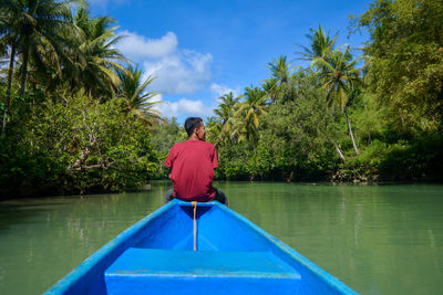 Rear view of man sitting in boat on lake
