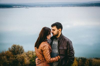 Young couple standing against sky