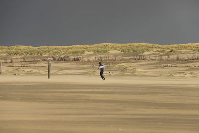 Man running at beach against clear sky