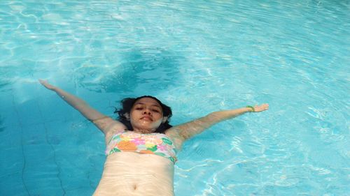 High angle portrait of woman floating in swimming pool