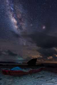 Abandoned boat at beach against sky at night