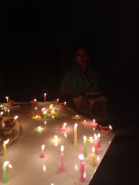 Young woman with illuminated candles in dark room