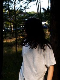 Rear view of woman standing against trees