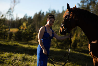 Portrait of woman standing by horse at forest