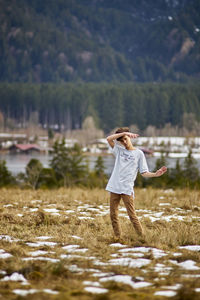 Rear view of woman standing on field against sky