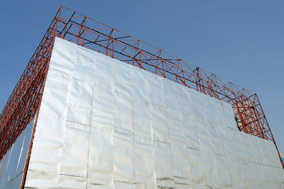 Low angle view of built structure at construction site against clear blue sky