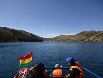 Rear view of people on lake against blue sky