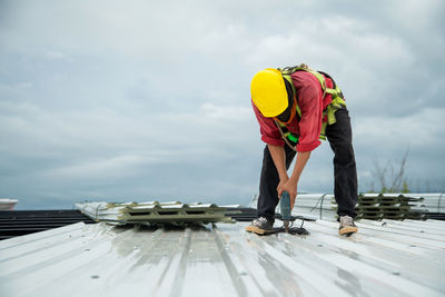 Asian construction workers are installing metal roofing sheets for industrial roof installations.