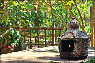 Lit diya on wall against trees