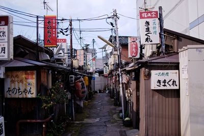 Wet alley amidst houses against sky