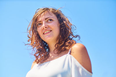 Low angle view of beautiful young woman with brown hair against clear sky