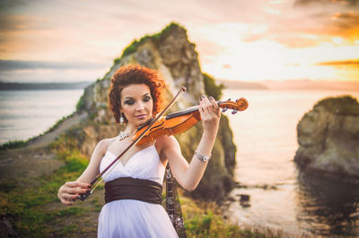 Portrait of young woman playing at beach during sunset