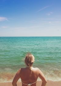 Rear view of shirtless boy on beach against clear blue sky