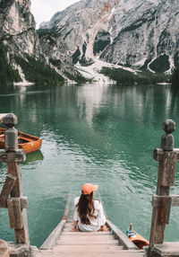 Rear view of woman sitting on pier at lake 