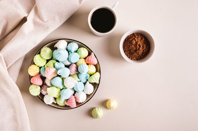 Multi-colored mini meringues on a plate on the table top view